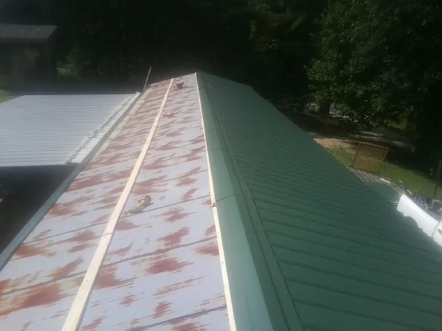 Old rusted panels beside newly installed green metal roofing — Wind Damage Roof Repair by Roofing Brothers in Gloucester City