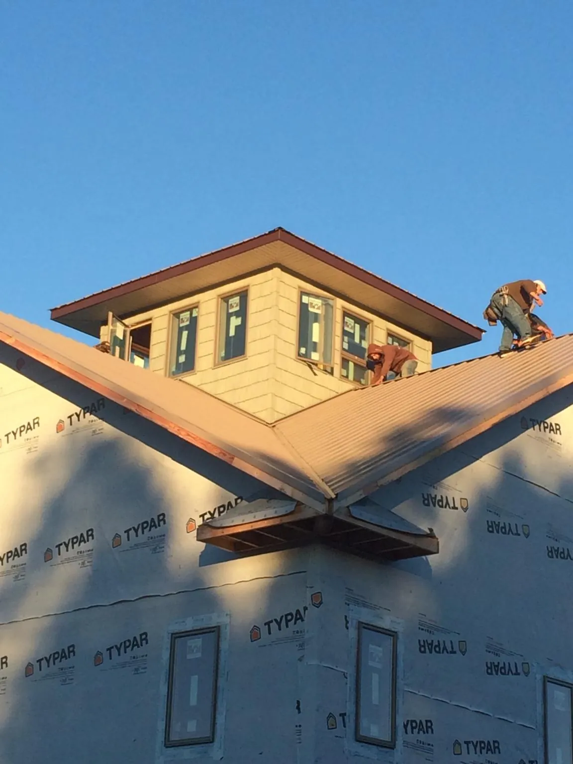 Roofers working around a rooftop cupola on a new metal roof at sunset — Roof Waterproofing in Gloucester City by Roofing Brothers